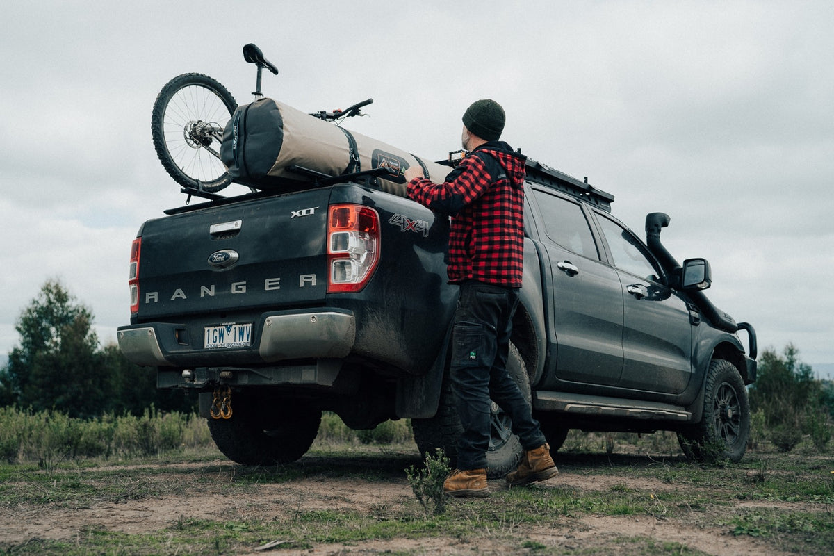 Person loading a bike onto a Ford Ranger truck in an outdoor setting